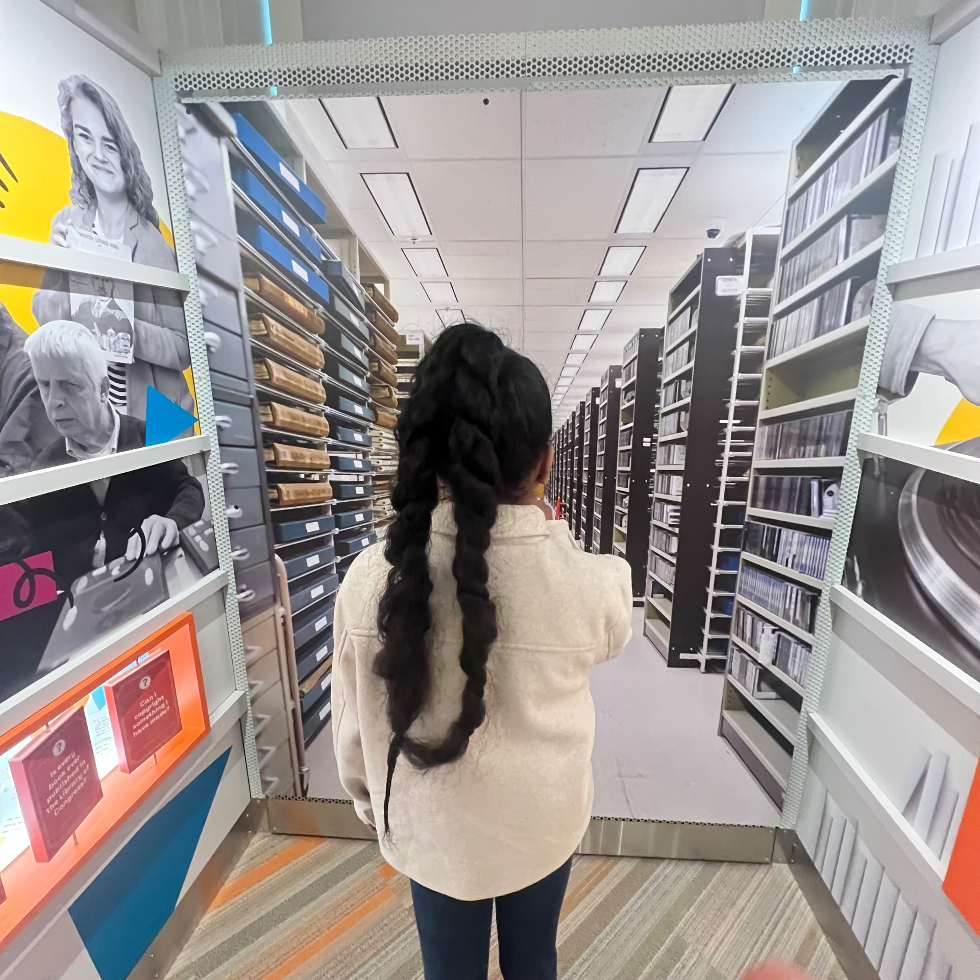 Ishara looking down a long aisle of Library of Congress collection shelves inside the exhibit