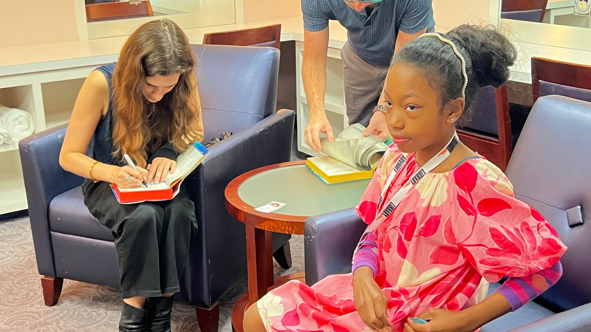 Katherine Rundell signing a book while Ishara looks on