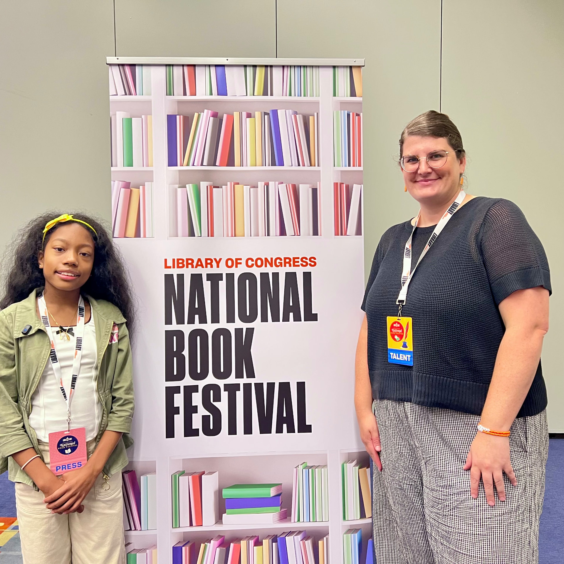 Ishara standing with author Geo Rutherford beside the National Book Festival banner