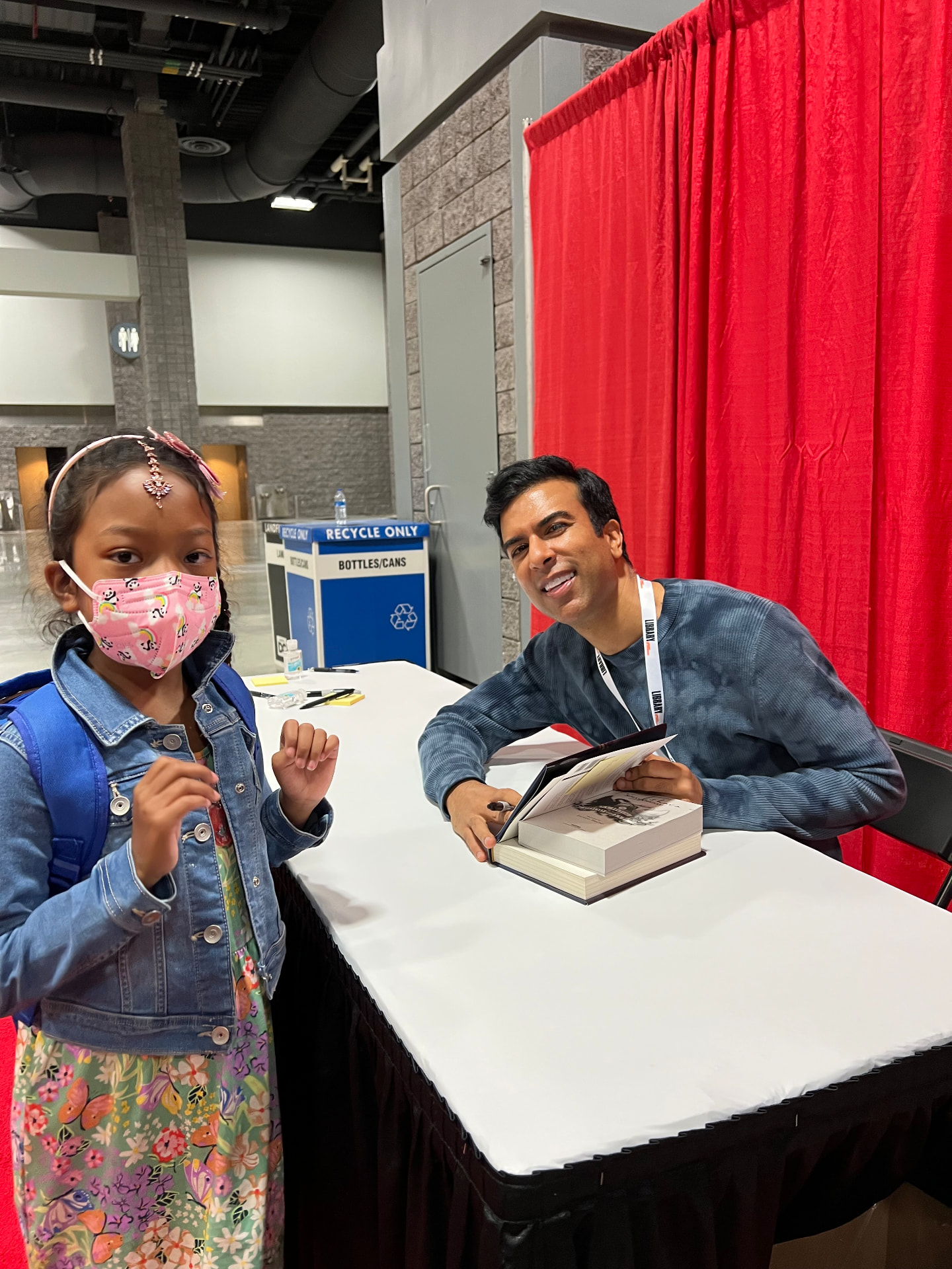 Ishara at an author's signing table getting a book signed