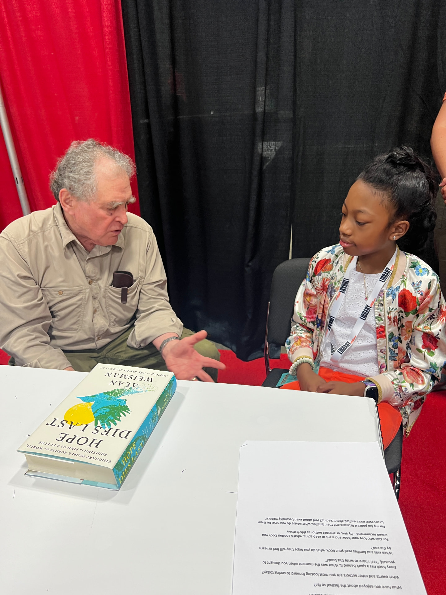 Ishara interviewing Alan Weisman with Hope Dies Last on the table