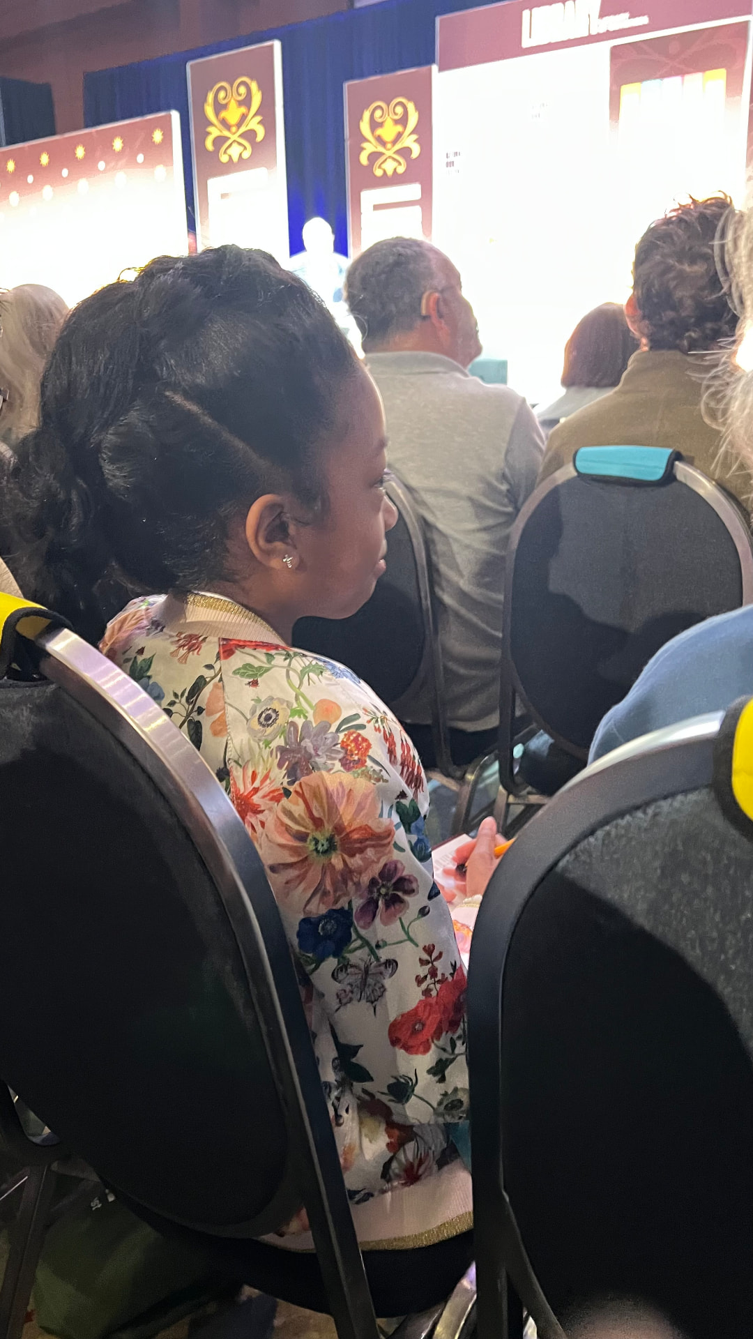 Ishara seated in the audience taking notes during a festival session