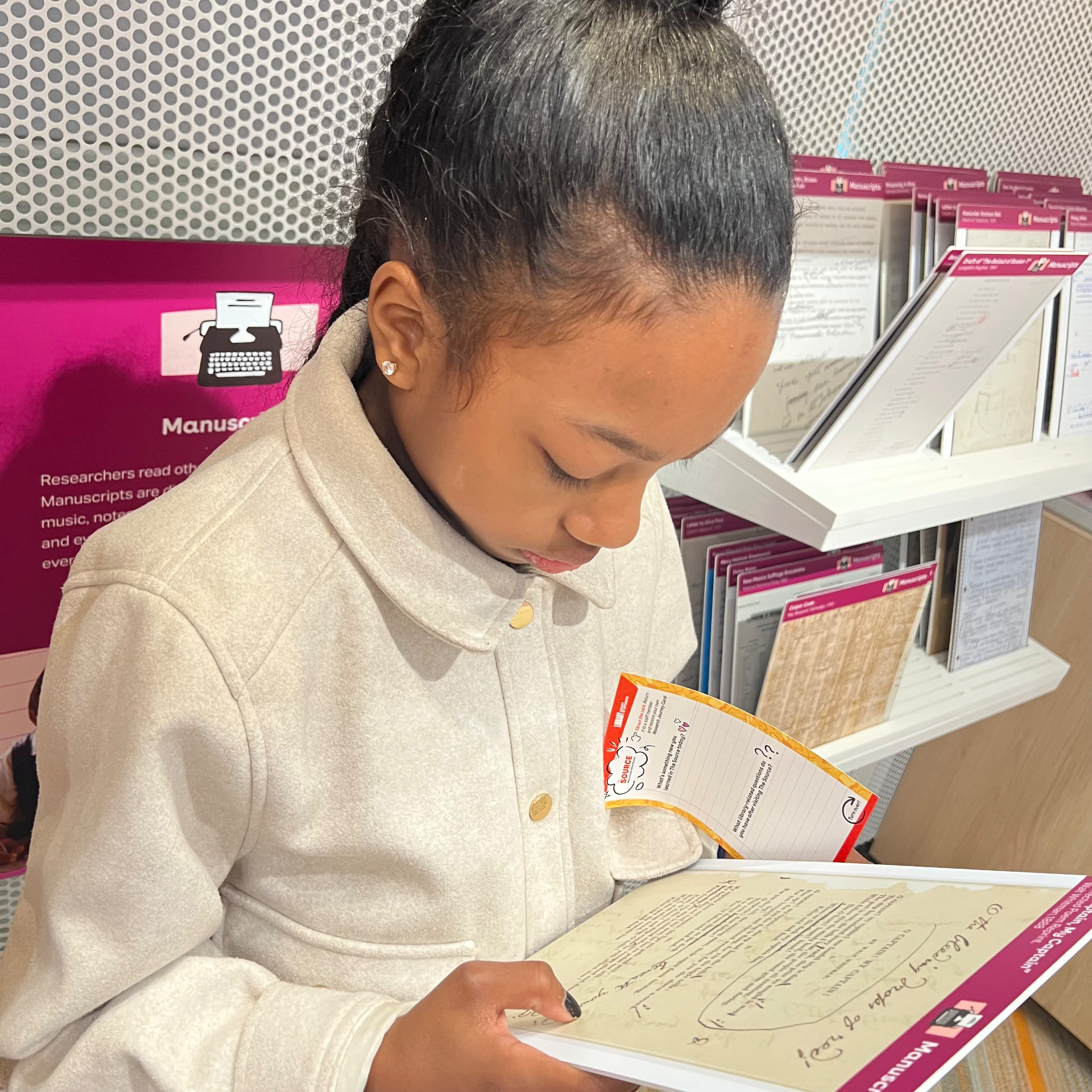 Ishara reading a manuscript facsimile at the manuscripts station inside The Source
