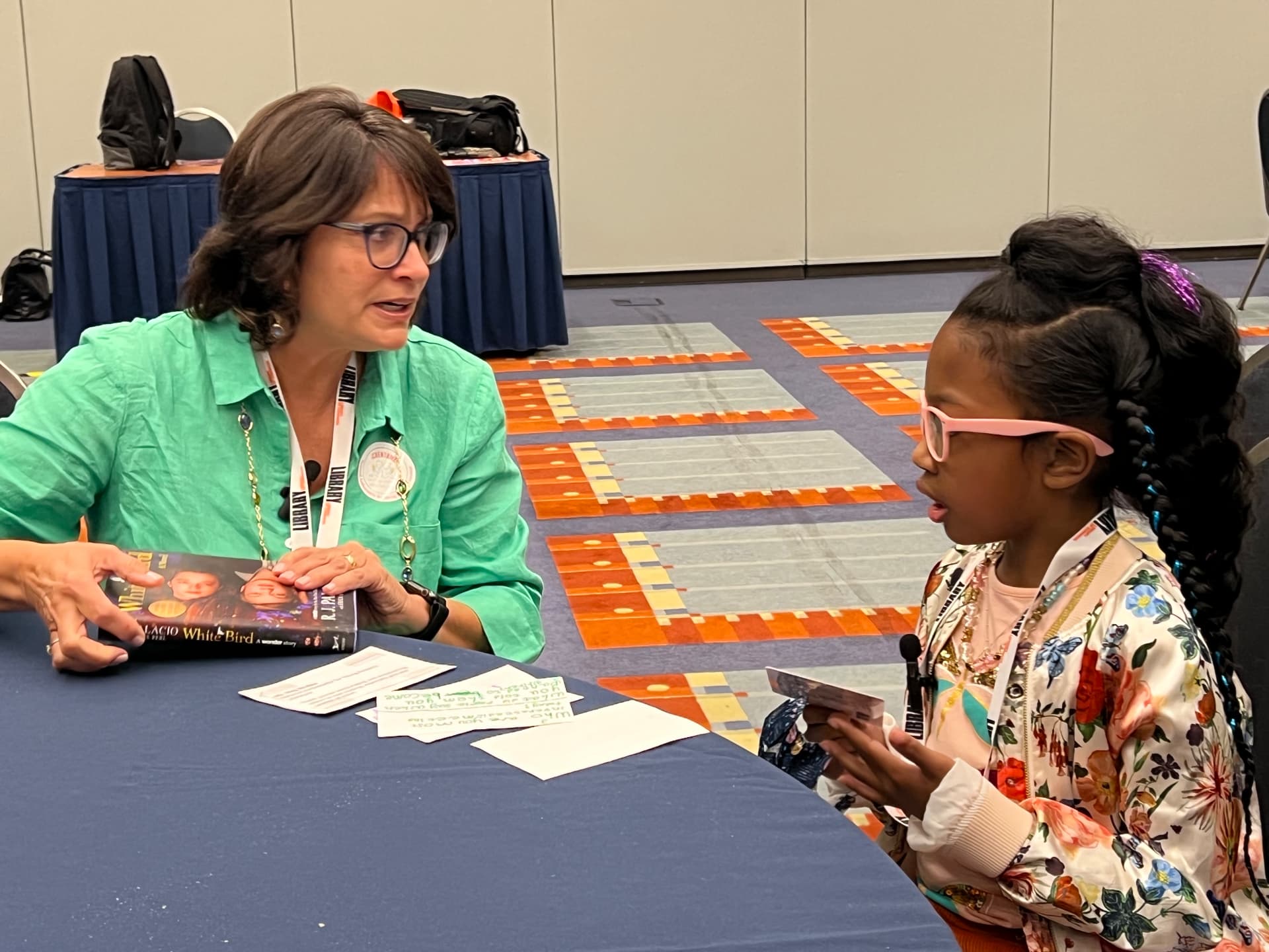 Ishara interviewing an author at a table with her question cards