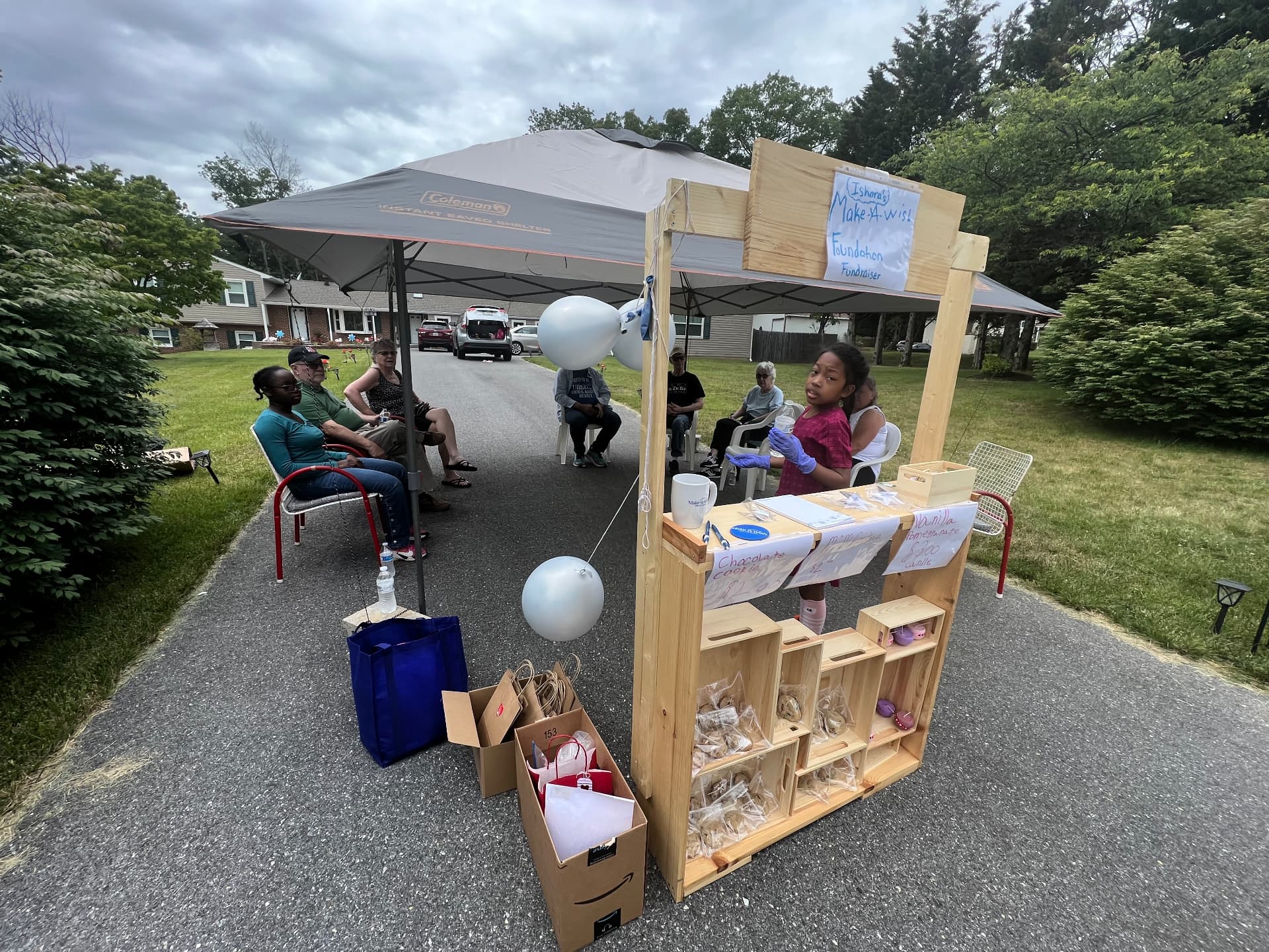 Ishara behind her cookie stand under a tent at the Make-A-Wish fundraiser