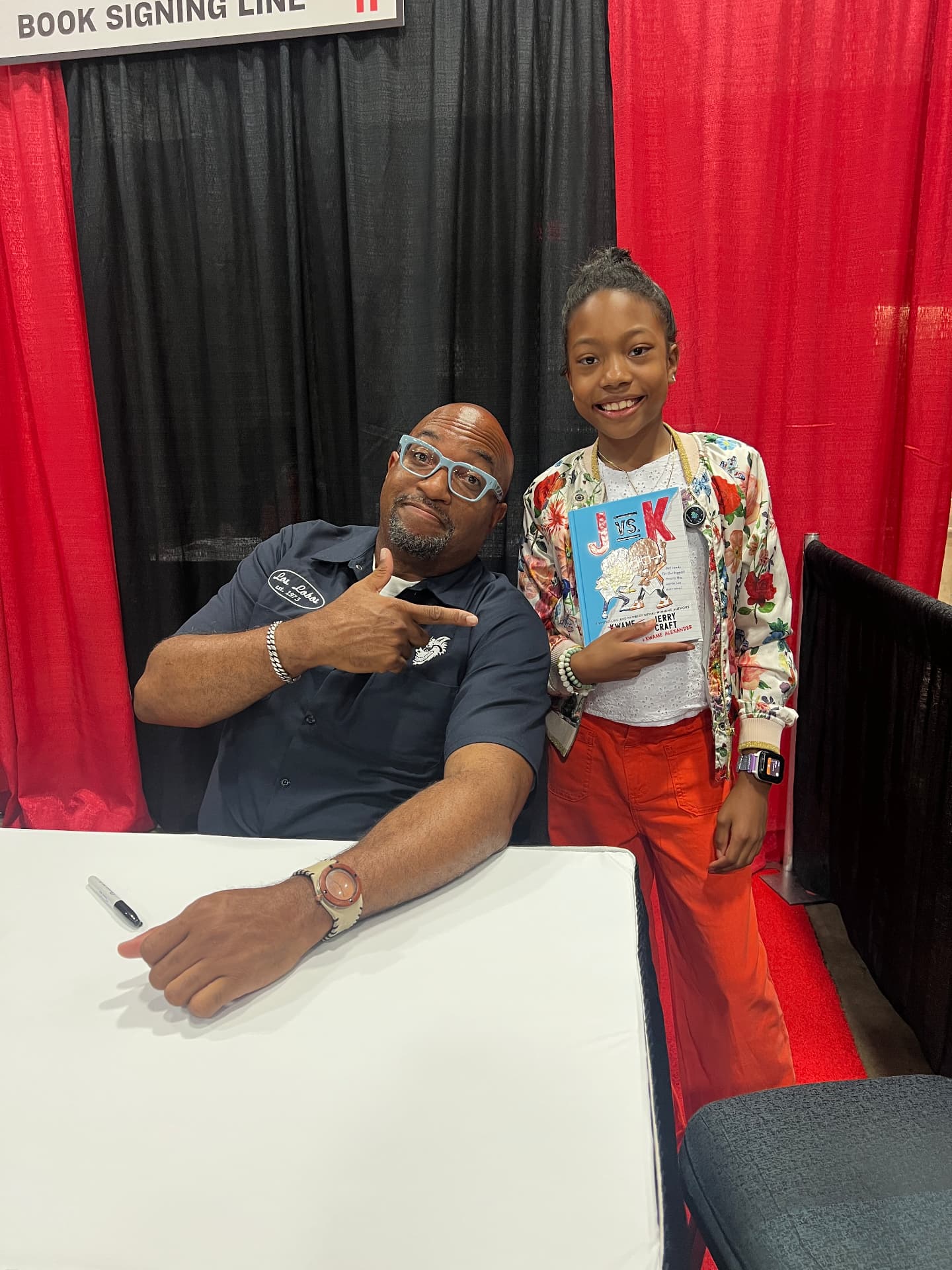 Ishara holding J vs. K next to author Jerry Craft at the book signing line