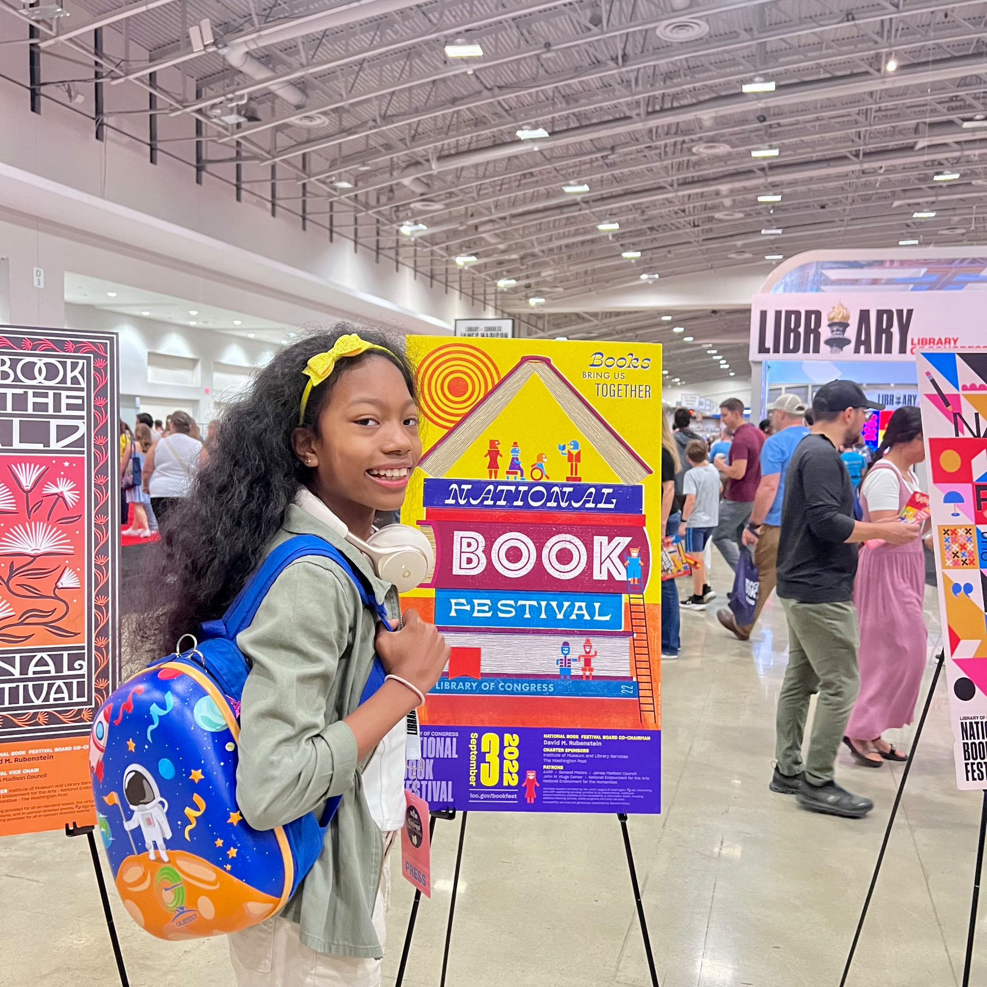 Ishara with her space backpack beside the 2022 National Book Festival poster display