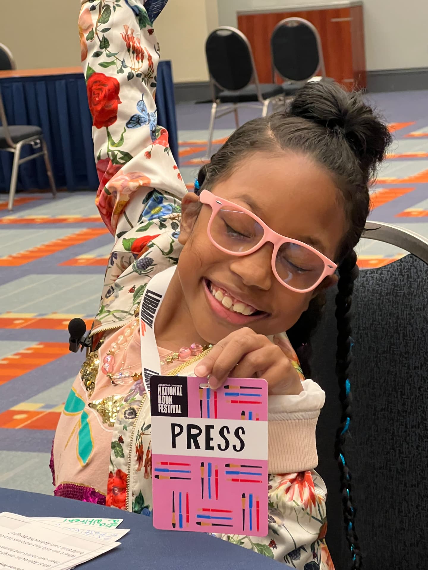 Ishara smiling and holding up her National Book Festival PRESS badge