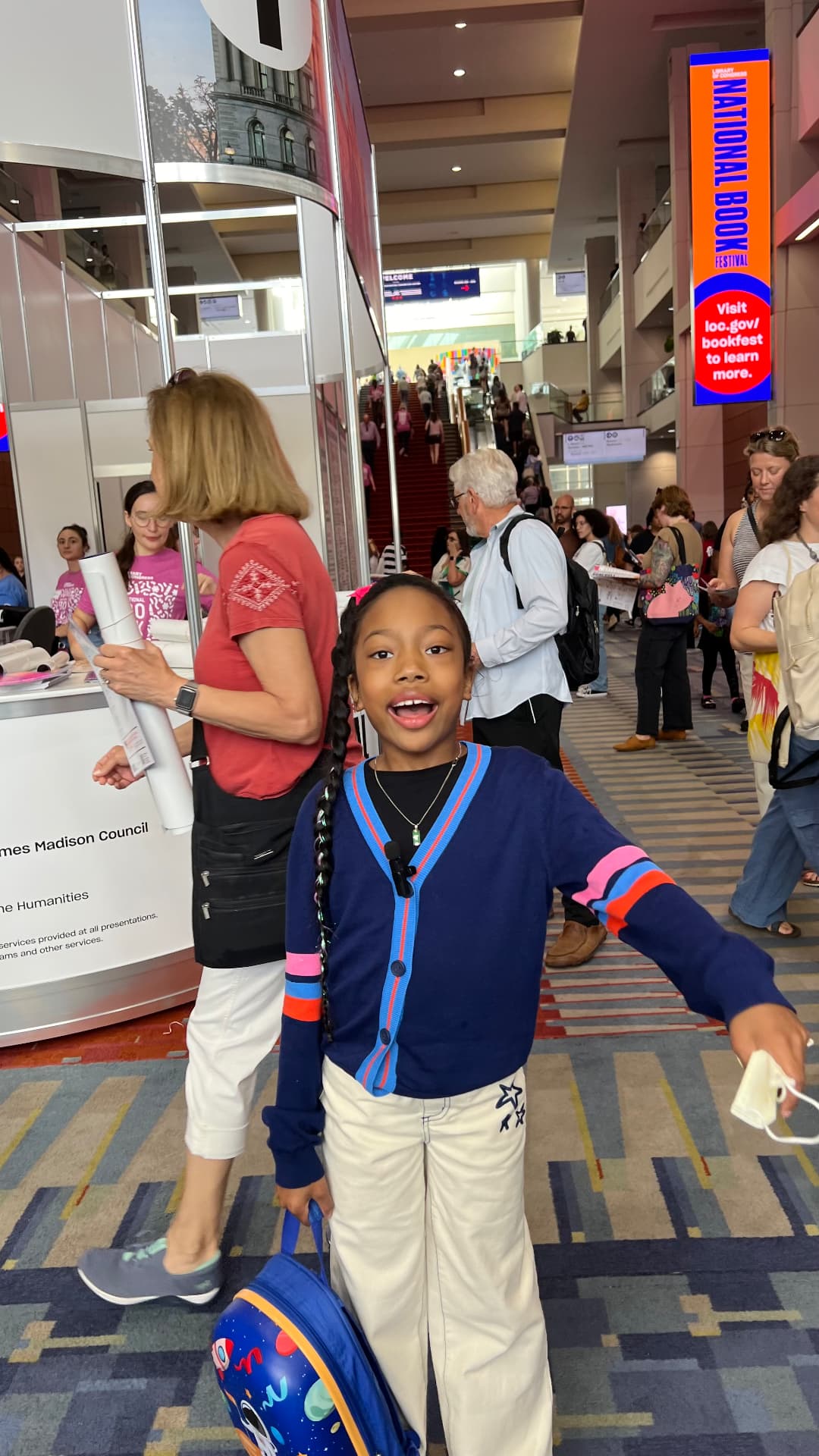 Ishara smiling with arms out under the National Book Festival banner