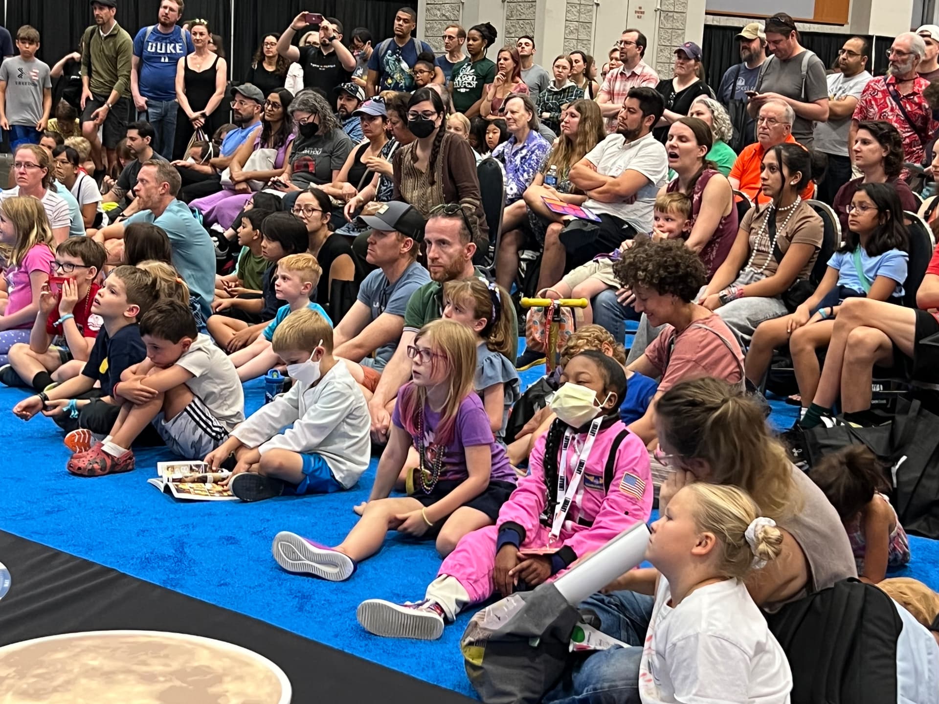 A large audience of kids and families seated on the floor at a National Book Festival presentation